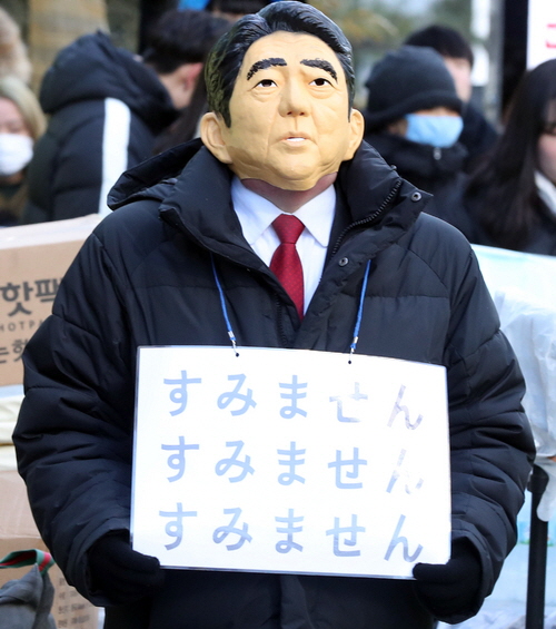 24일 오후 서울 종로구 옛 일본대사관 앞에서 열린 일본군 위안부 문제 해결을 위한 1319차 정기 수요시위에서 아베 신조 일본 총리의 탈을 쓴 참석자가 '미안합니다'(すみません)라고 적힌 피켓을 들고 있다.