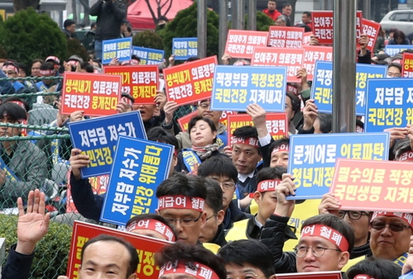 지난달 18일 서울 종로구 동화면세점 앞에서 열린 '국민건강수호 비대위 제1차 전국의사대표자대회' 참가자들이 문재인케어를 반대하는 구호를 외치고 있는 모습. / 뉴시스<br>