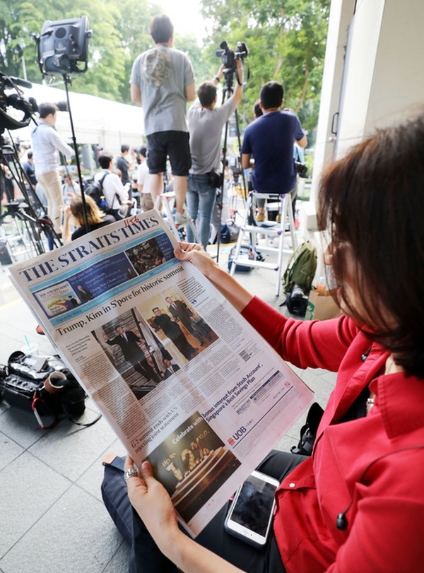 북미 정상회담을 하루 앞둔 11일 김정은 북한 국무위원장이 묵고 있는 싱가포르 세인트 리지스 호텔 앞에서 싱가포르 취재진이 자국 신문에 실린 도널드 트럼프 미국 대통령과 김정은 북한 국무위원장의 기사를 읽고 있다. 뉴시스