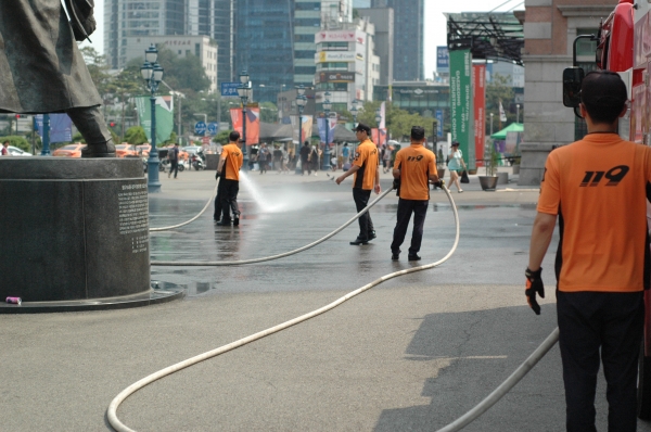 폭염으로 달궈진 광장 바닥에 살수작업을 하는 서울중부소방서 소속 119 대원들 ⓒ스트레이트뉴스