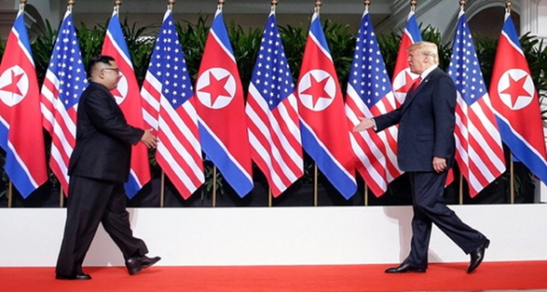 북미 정상회담이 열린 지난 6월 12일 오전 싱가포르 센토사섬 카펠라 호텔 회담장에서 북한 김정은(왼쪽) 위원장과 미국 도널드 트럼프 대통령이 역사적인 회담에 앞서 세기의 악수를 하기 위해 걸어오며 손을 내밀고 있는 모습. 싱가포르 통신정보부 제공