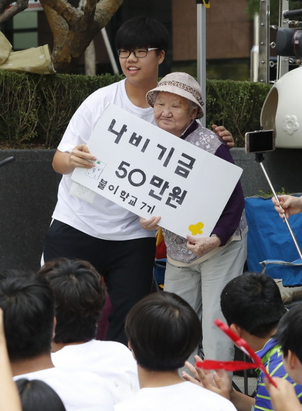 12일 서울 종로구 일본대사관 앞에서 열린 제1352차 일본군 성노예제 문제해결을 위한 정기 수요시위에서 중등 대안 불이학교 학생들이 길원옥 할머니에게 '나비 기금'을 전달하고 있다.