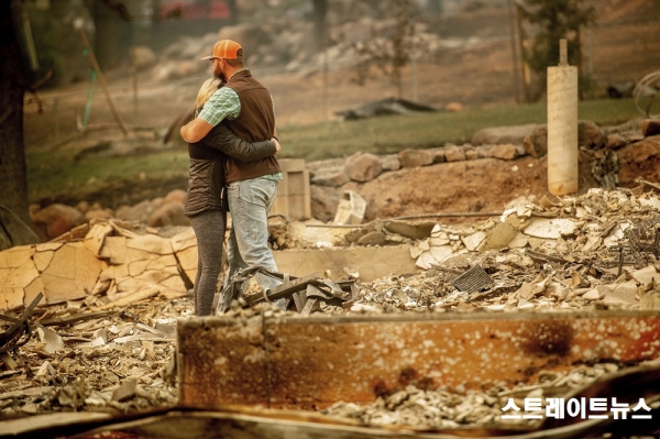 화마가 휩쓸고 지나간 뒤 잿더미로 변해버린 집터에서 부둥켜안은 부부. 남부 캘리포니아(자료:pressherald) ⓒ스트레이트뉴스