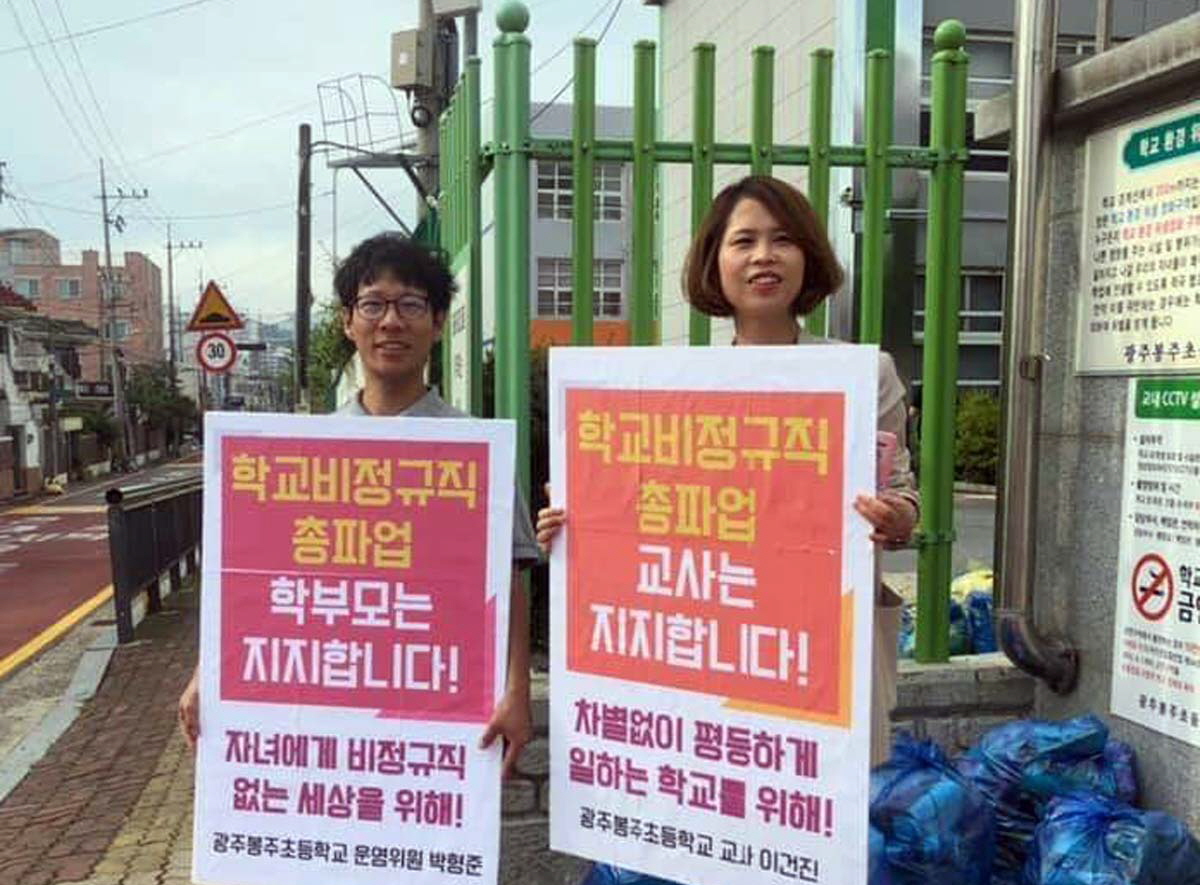 광주 봉주초교 학부모와 교사가 3일 학교 앞에서 '학교 비정규직 총파업을 지지한다'는 내용의 피켓을 들고 서 있다. 학부모 제공