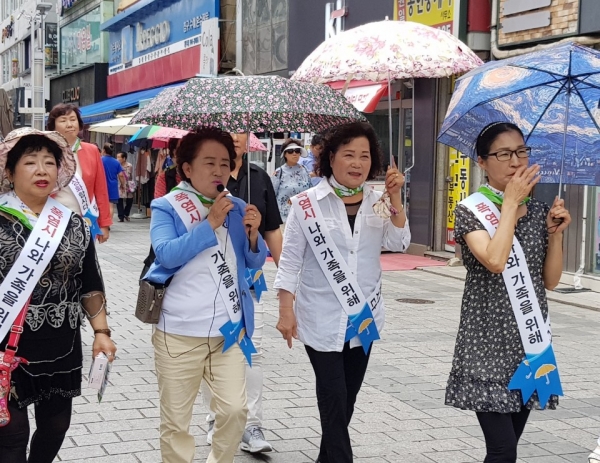 유선자 원주시의원이 마이크를 들고 '폭염 시 양산(우산)쓰기 일상화 운동' 거리 홍보 캠페인을 펼치고 있다.