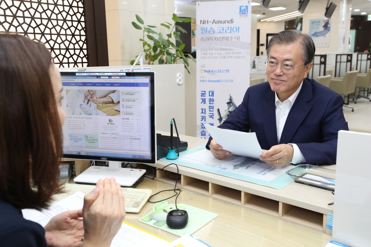 문재인 대통령이 26일 서울 중구 NH농협은행 본점에서 '필승 코리아 펀드'에 대한 직원의 설명을 듣고 있다.