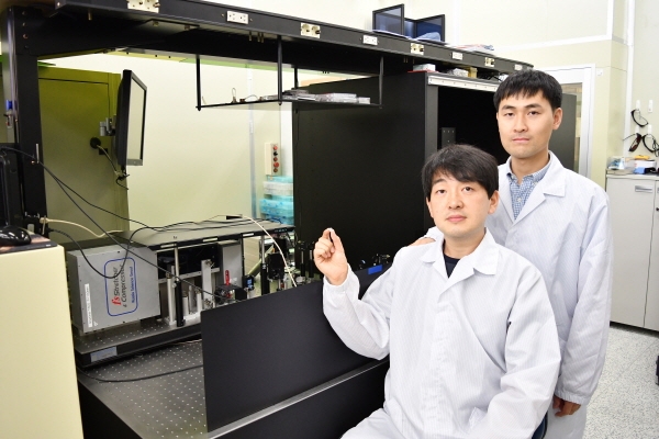 연구개발자인 정보수 선임(앞)과 이병학 선임이 펨토초 레이저 장비 앞에서 표면처리 된 티타늄을 들고 있다