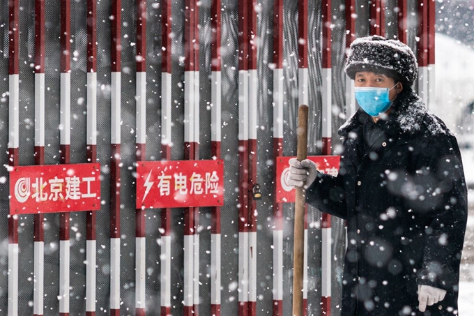 중국 베이징에서 6일 마스크를 쓴 남성이 눈을 치우고 있다. 연합뉴스