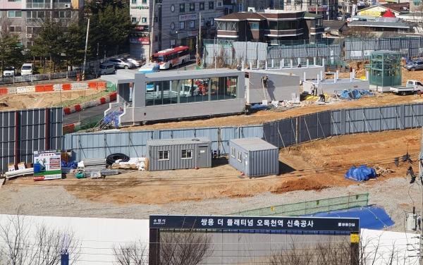 ◇경기 수원시 권선구 오목천동 482-2번지 일대에 총 930가구 규모로 지어질 아파트 단지인 '쌍용 더 플래티넘 오목천역' 공사 현장의 서남쪽 펜스 및 주변부. 수인선 오목천역 출구가 둘 보인다. 단지 주변 수인선은 지하로 건설되며, 과거 선로가 있던 지상부는 서울의 '경의선숲길' 또는 '경춘선철길' 등처럼 공원화가 이뤄진다. (사진=이준혁 기자)