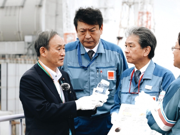 후쿠시마 원전 현장을 방문한 스가 요시히데 신임 총리가 방사능 오염수가 담긴 병을 들고 관계자에게 마셔도 되느냐고 묻고 있다. (사진=교도통신/연합뉴스)
