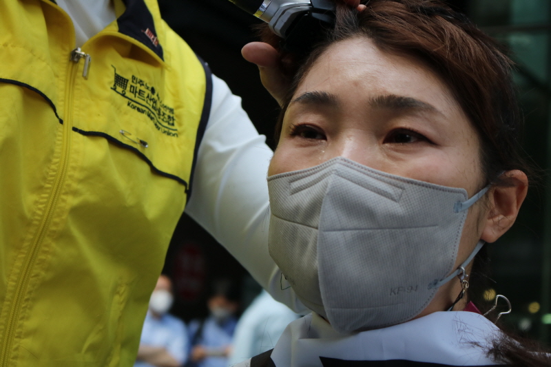 홈플러스 여성노동자들이 13일 오후 서울 광화문 디타워 MBK 앞에서 운영사 MBK파트너스의 주요 점포 폐점 매각을 규탄하며 집단삭발을 하고 있다.