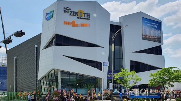 ◇양산시 물금읍에 마련된 '양산 두산위브더제니스' 견본주택. 견본주택 입구에 부착된 '사회적 거리두기'에 적극 동참해달란&nbsp;현수막 내용과 다르게&nbsp;견본주택 입구에는 견본주택을 들어가려는 사람들과 견본주택 관람을 마치고 나오는 사람들을 대상으로 호객행위를 시행하는 MGM이 즐비했다. (사진=이준혁 기자)