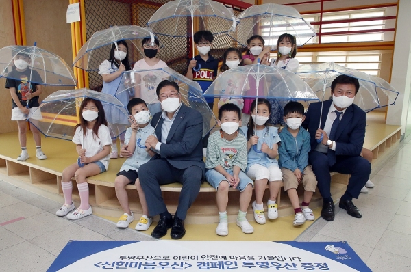 지난 6일 서울시 중구 서울남산초등학교에서 진행된 ‘신한마음우산’ 기부식에 참석해 학생들과 함께한 신한은행 안준식 부행장(가운데)와 한국어린이안전재단 정영균 사무총장(제공=신한은행)