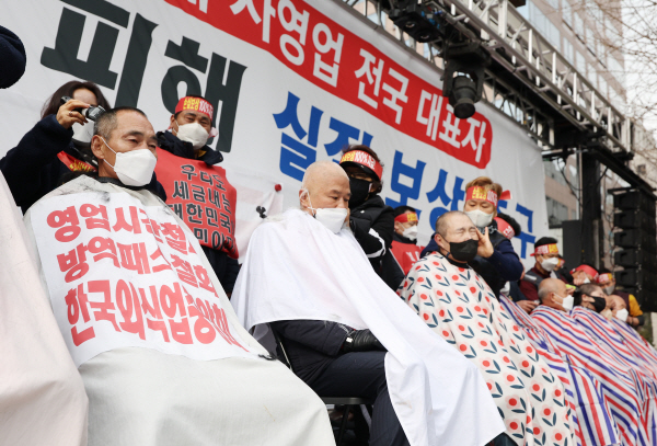 '코로나 피해 자영업 총연대'에 소속된 자영업자들이 지난달 25일 여의도 국회의사당 인근 국민은행 앞에서 손실보상 소급적용 등을 요구하며 삭발식을 하고 있다. 연합뉴스