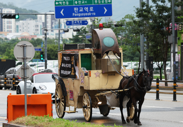 카카오게임즈의 '우마무스메:프리티 더비' 국내 이용자들이 게임사 측의 운영 방침에 반발하는 항의 문구 현수막을 붙인 마차가 지난달 29일 오전 카카오게임즈 본사가 위치한 경기도 성남시 판교역 인근 도로를 달리고 있다. 연합뉴스