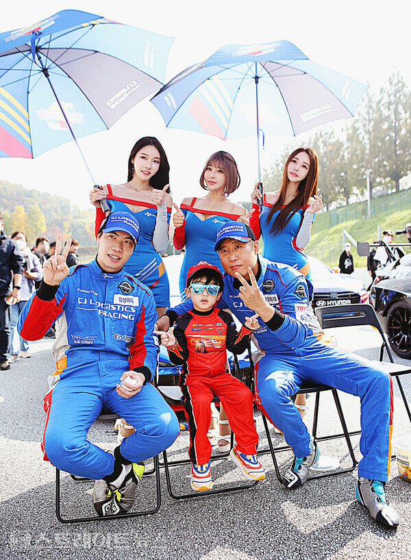 ▲CJ로지스틱스 레이싱팀 (아래 왼쪽부터) 문성학-정연일과 (위 왼쪽부터) 레이싱 모델 유리안-진하진-서진아가 그리드워크 이벤트에서 어린이와 기념촬영을 하고 있다.(2022 CJ대한통운 슈퍼레이스 챔피언십 8라운드 ) / 양용은 기자 taeji1368@naver.com