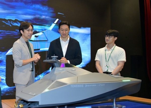 정기선 HD현대 부회장(가운데)이 미래기술원 연구원들로부터 팔란티어와 공동개발 중인 무인수상정(USV) '테네브리스'에 대한 설명을 듣고 있다. HD현대 제공