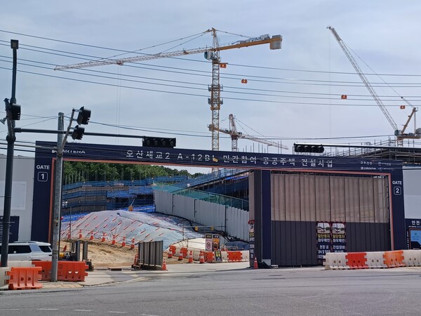 왕복2차선 서부로와 발안로가 교차하는 지점에서 바라본 ‘오산 세교 아테라’ 건설현장 주출입구(GATE 1). 1205동이 위치할 뒤편 야산 쪽에 H빔 천공공사 및 토류판 설치공사가 끝난 옹벽이 보인다. 바로 옆에 공사 중인 단지는 지난해 청약에서 0.85 대 1로 미달 났던 ‘오산세교 힐데스하임’이다. 김태현 기자