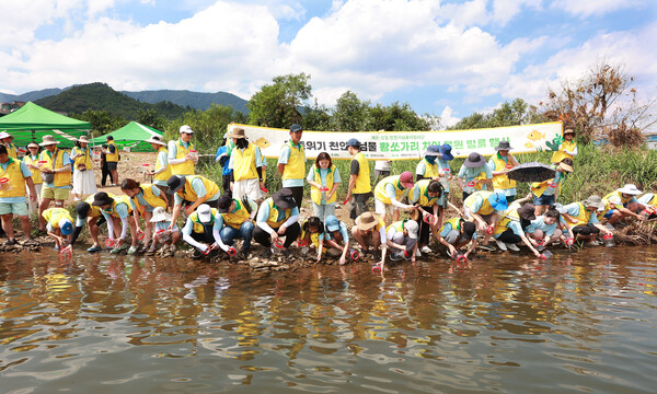 에쓰오일(S-OIL)의 임직원 가족과 대학생 천연기념물지킴이단 등 봉사활동 참가자들이 황쏘가리 치어를 방류하고 있다. 에쓰오일 제공