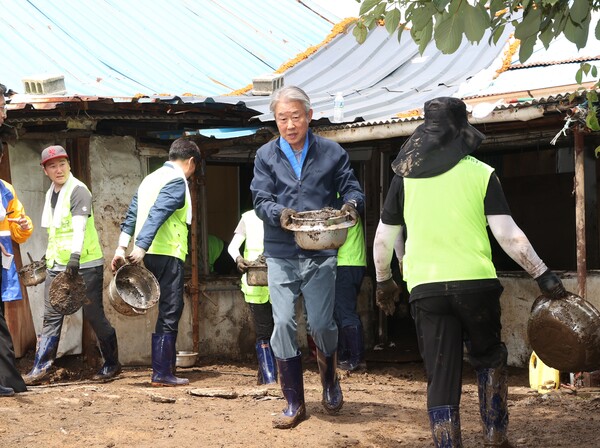양은남비에 흙을 담아 퍼다나르며 일손을 돕는 강호동 회장. 농협 제공.