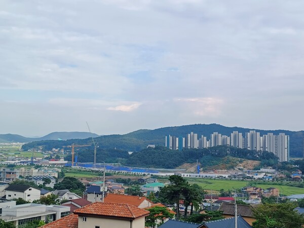 두산건설이 인천 강화군 선원면 창리 501번지 일원에 공급하는 '두산위브 센트럴파크 강화' 건설현장을 맞은편 남산  중턱에 자리한 '호텔 에버리치' 쪽에서 내려다 본 모습. 야산 뒤쪽 창리근린공원 너머 ‘강화 서희스타힐스 1·2단지’가 보인다. 현지에서는 인근 대비 고분양가와 완전치 않은 교통 및 교육 등의 여건으로 인해 '미분양 예약'이라는 평가가 나온다. 김태현 기자