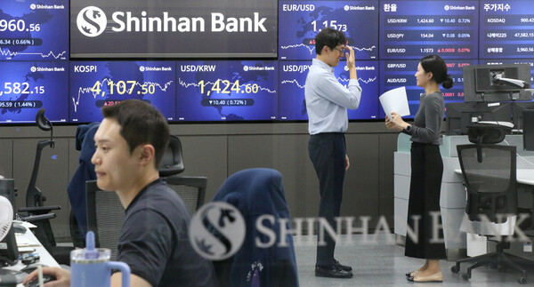 4100선을 넘긴 코스피를 나타내는 전광판 앞에서 담소 나누는 딜링룸 직원들. 신한은행 제공.