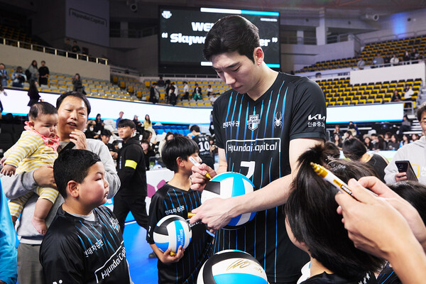 스카이워커스 유니폼을 입고 배구공에 사인을 받으며 즐거워하는 어린이들. 현대캐피탈 제공.