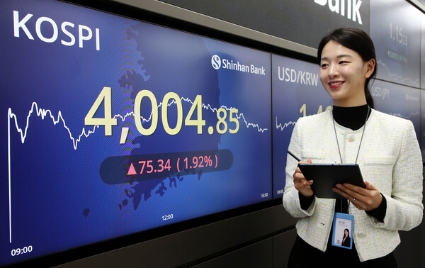 급등한 코스피 현황판 앞에서 웃고 있는 신한은행 딜링룸 직원. 신한은행 제공.